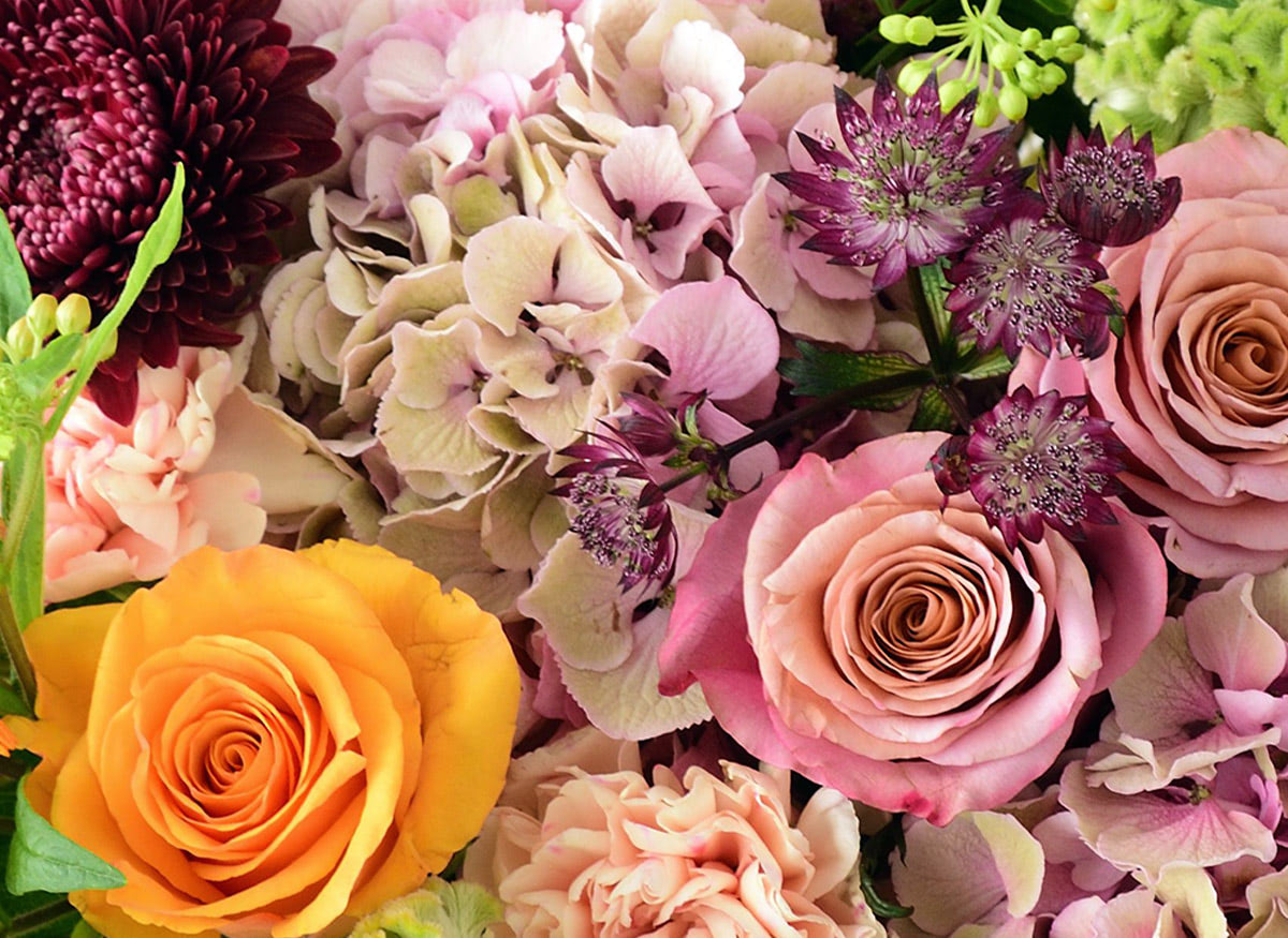 Autumn hues abound in this orange, pink, auburn and green floral arrangement